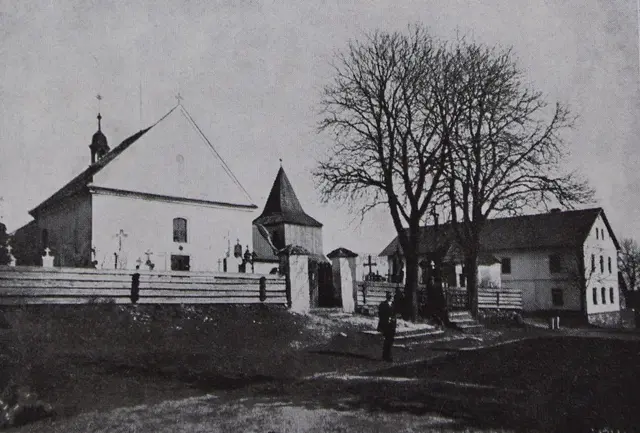 Stará fotografie kostela se zvonicí za hřbitovní zdí a holými stromy