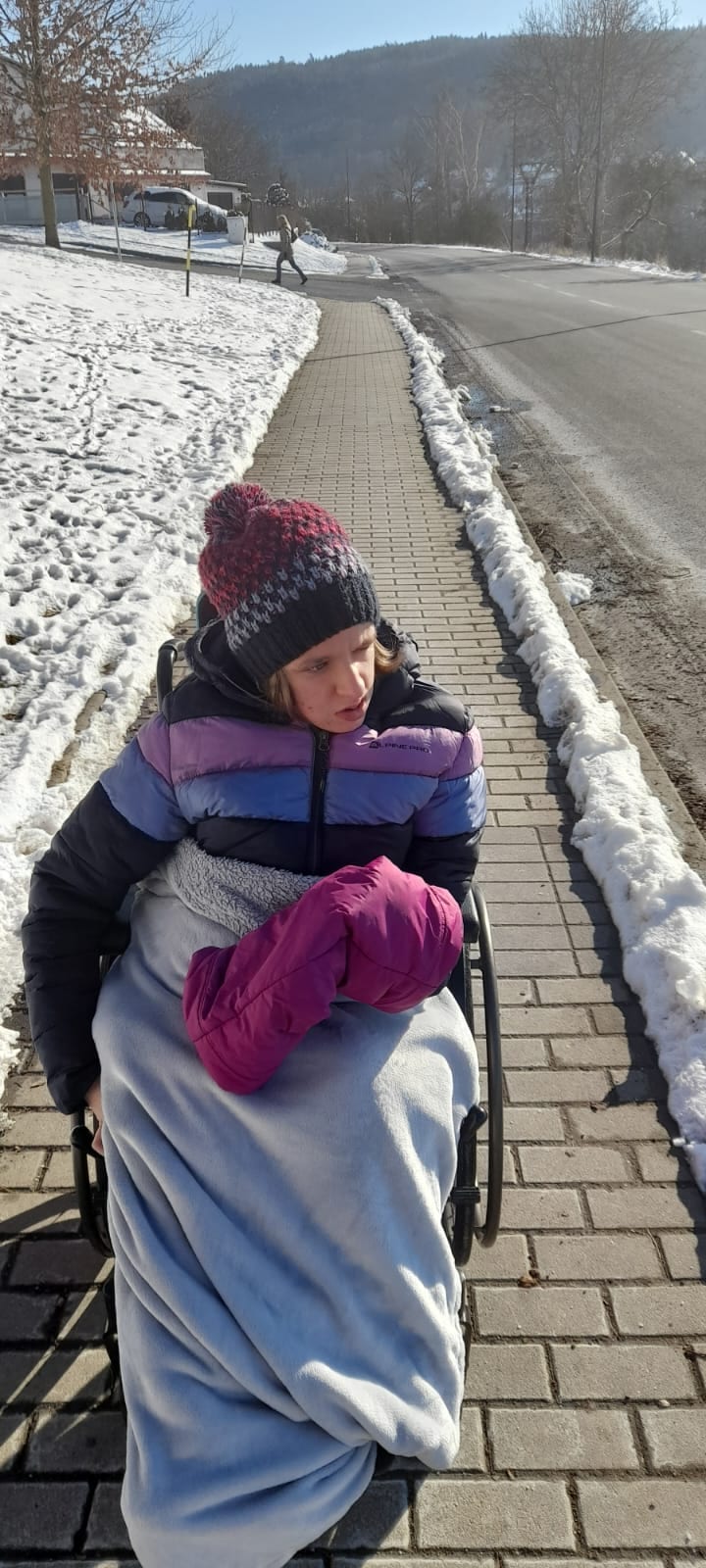 Terezka v zimě na vozíku zabalená v dece na chodníku