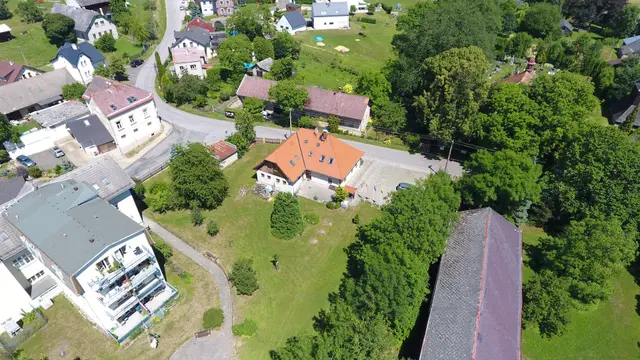 Bytový dům s balkony a dům s oranžovou střechou ve středu Vlastibořic